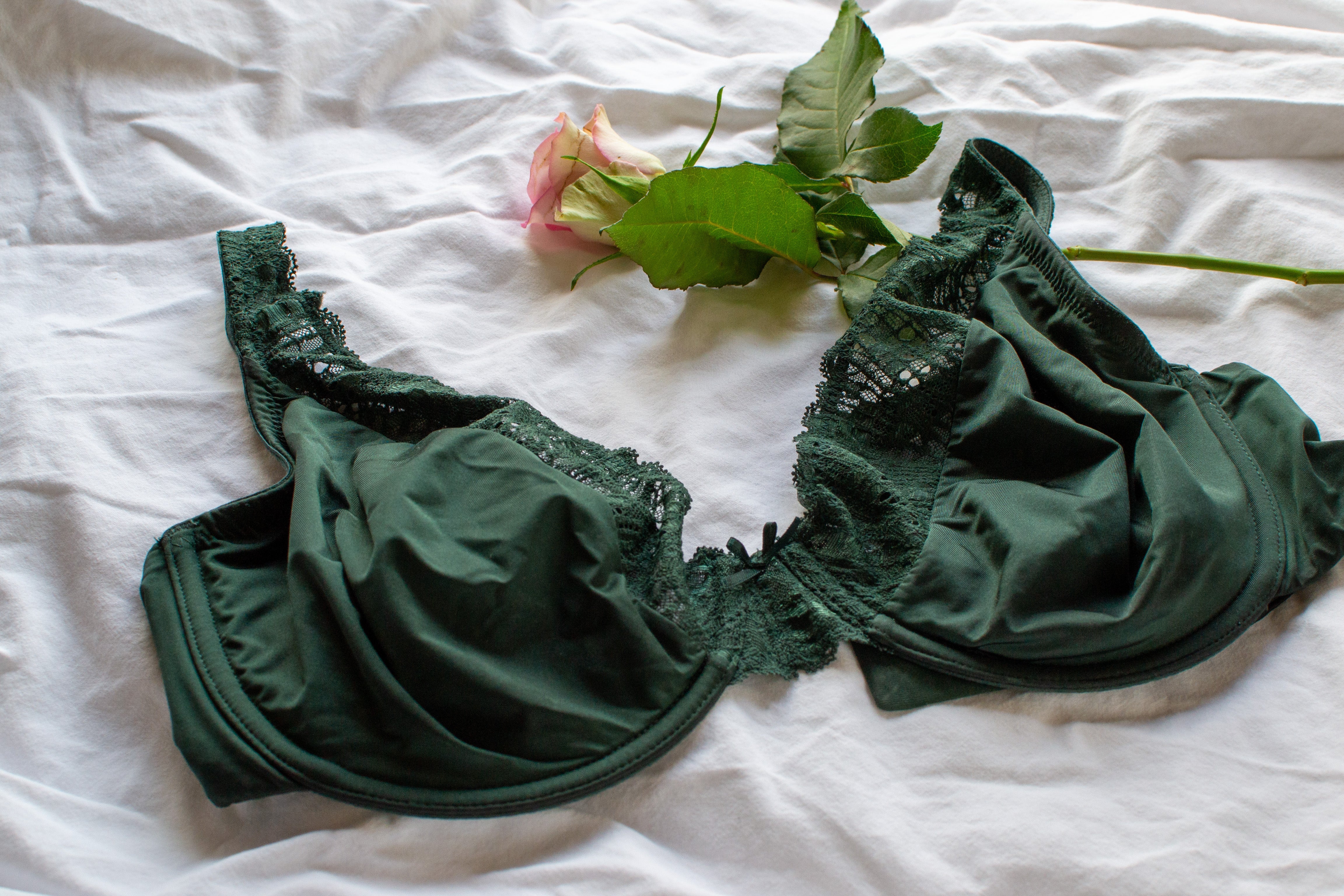 soutien-gorge vert posé sur un lit avec une fleur 